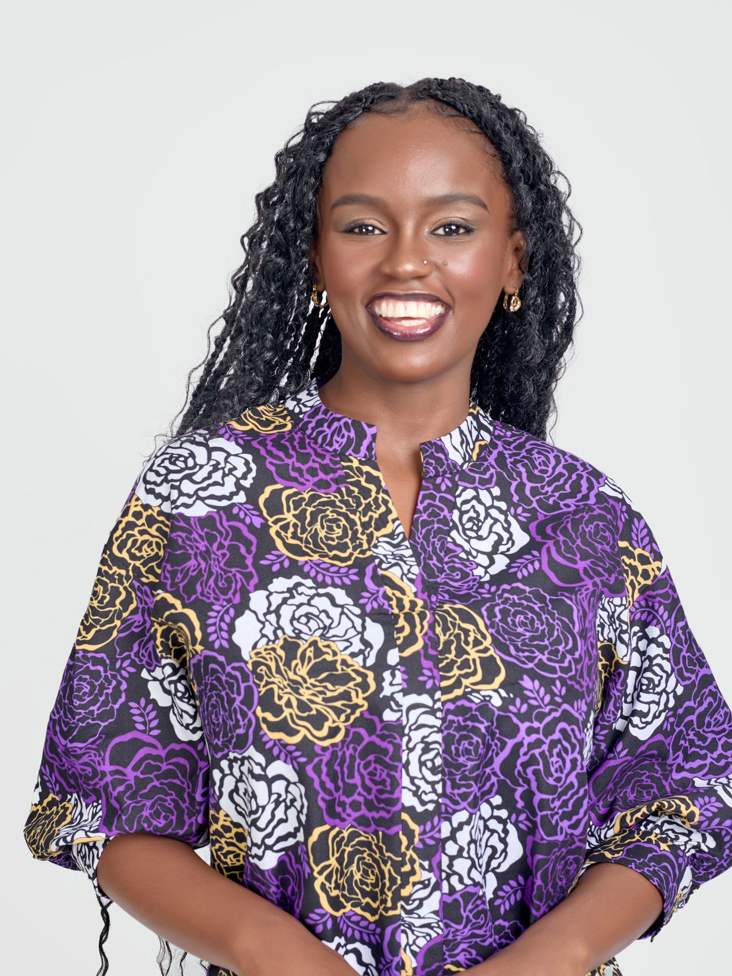 Woman wearing a purple floral patterned shirt against a white background